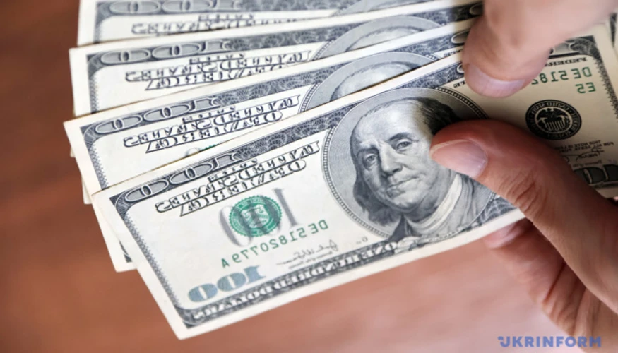 Банкноти долара США та євро поряд із таблицею офіційних курсів